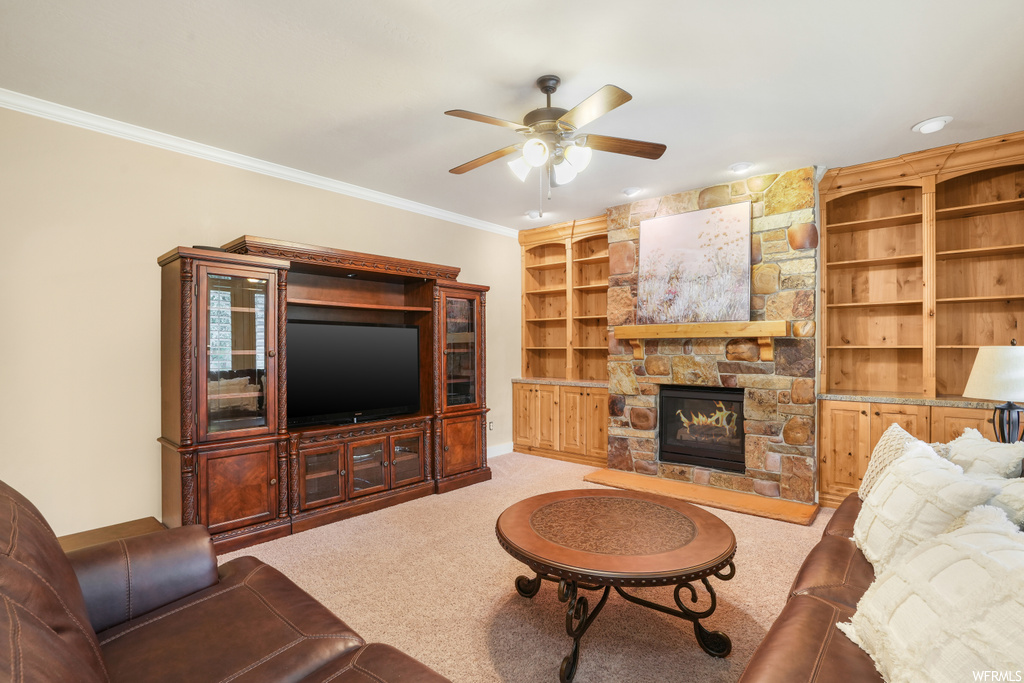 Carpeted living room featuring ceiling fan, a fireplace, built in features, and crown molding