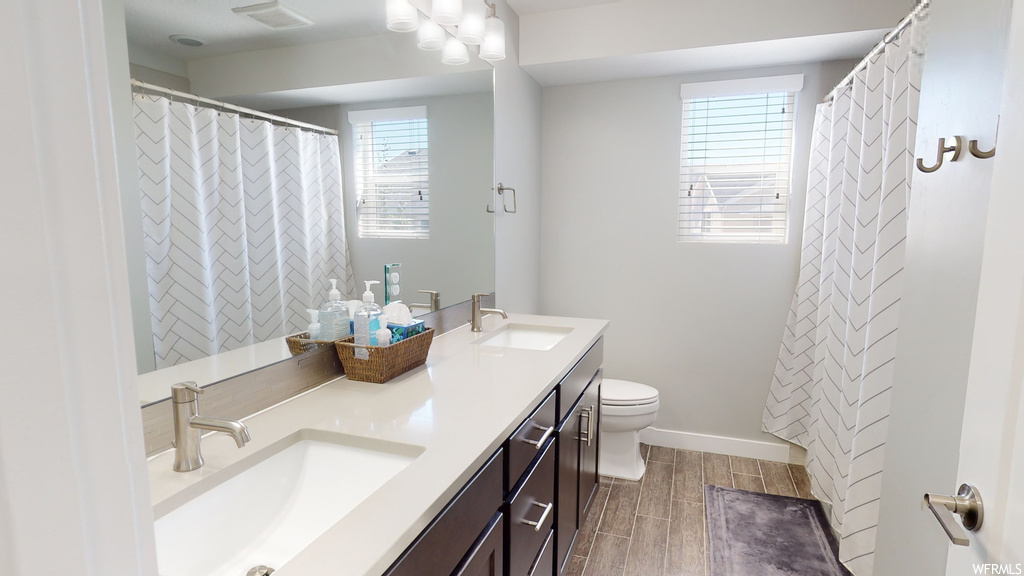 Bathroom featuring mirror, double large sink vanity, and plenty of natural light