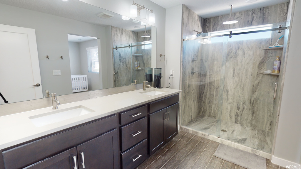 Bathroom featuring double vanity, mirror, and a shower with shower door