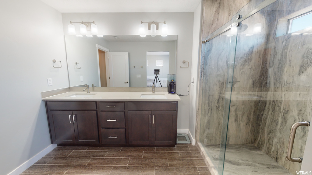 Bathroom featuring light tile floors, dual large vanity, an enclosed shower, and mirror