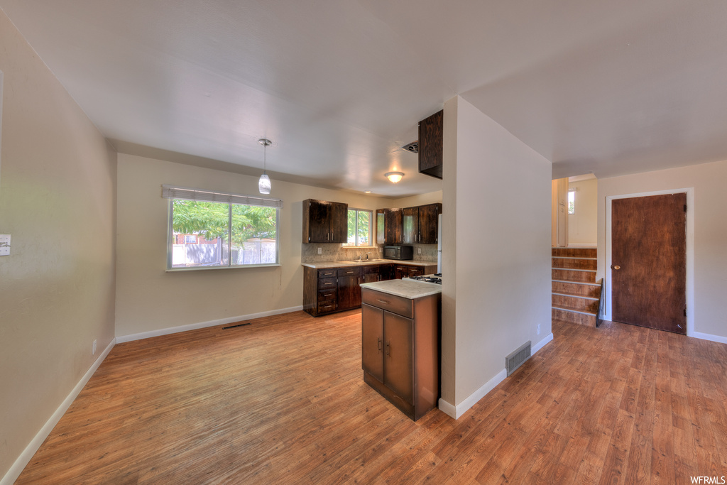Kitchen with dark brown cabinets, light parquet floors, backsplash, and light countertops