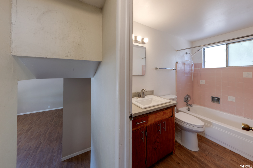 Full bathroom with wood-type flooring, vanity, tiled shower / bath combo, and mirror