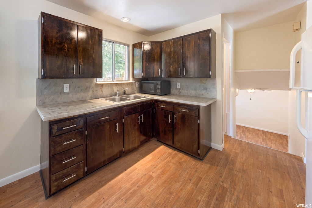 Kitchen featuring dark brown cabinets, backsplash, light countertops, and light hardwood floors
