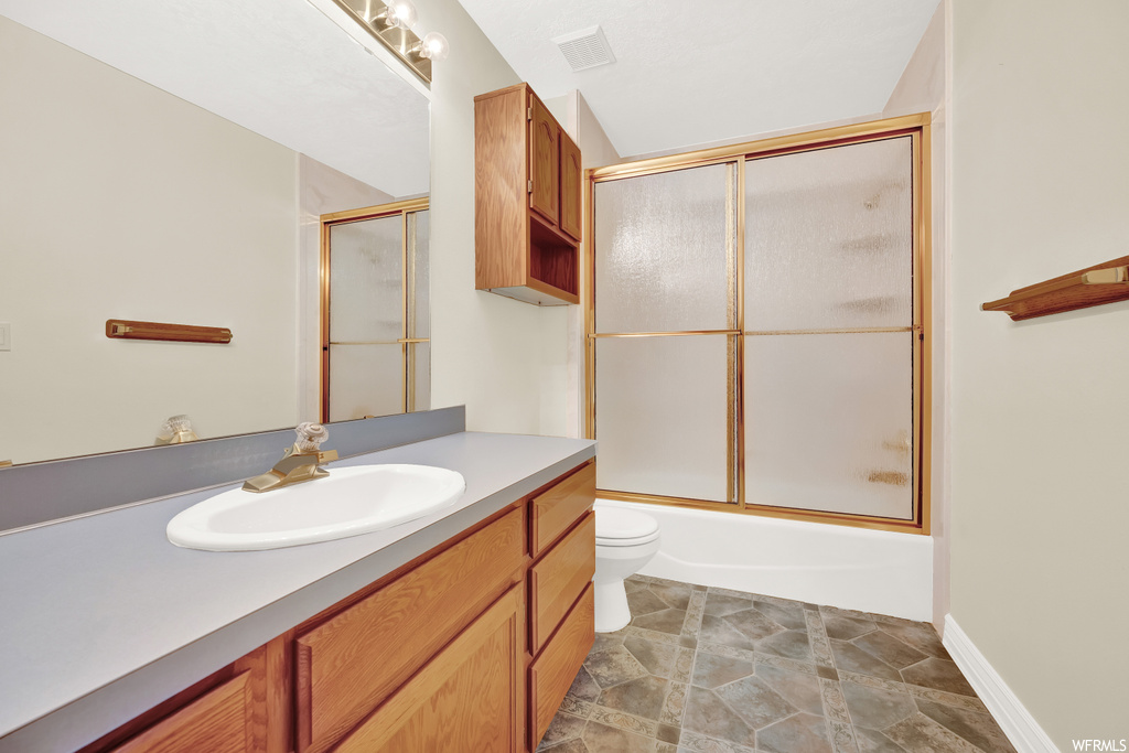 Full bathroom with mirror, tile flooring, bath / shower combo with glass door, and oversized vanity