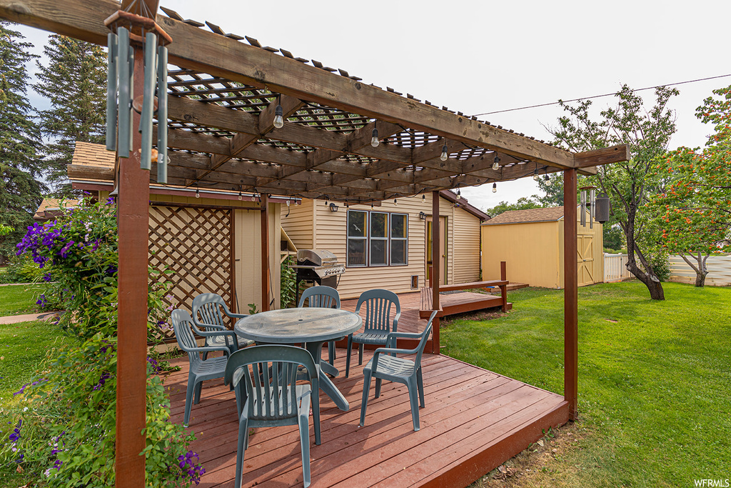 Deck featuring a pergola, a yard, and a shed