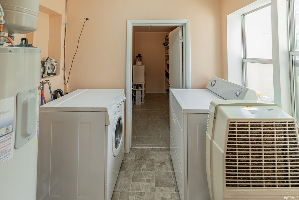 Clothes washing area with light tile floors, washer and dryer, and electric water heater