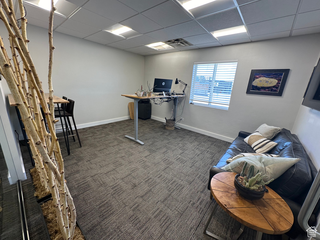 Office area with a paneled ceiling and dark carpet