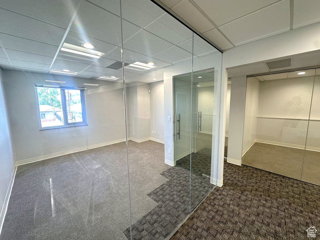 Basement with a drop ceiling and dark colored carpet