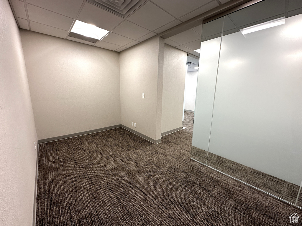 Spare room featuring dark carpet and a drop ceiling