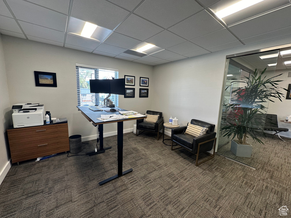 Home office with a drop ceiling and dark colored carpet