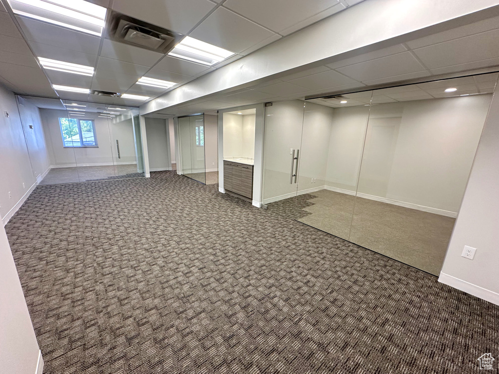 Basement featuring dark colored carpet and a paneled ceiling