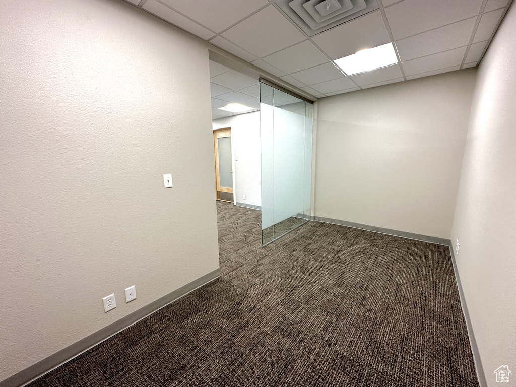 Unfurnished room featuring a paneled ceiling and dark colored carpet