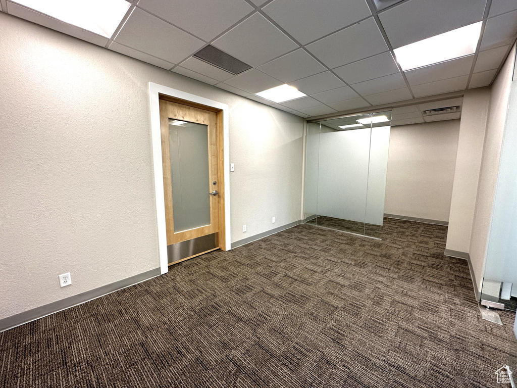 Basement featuring dark colored carpet and a paneled ceiling