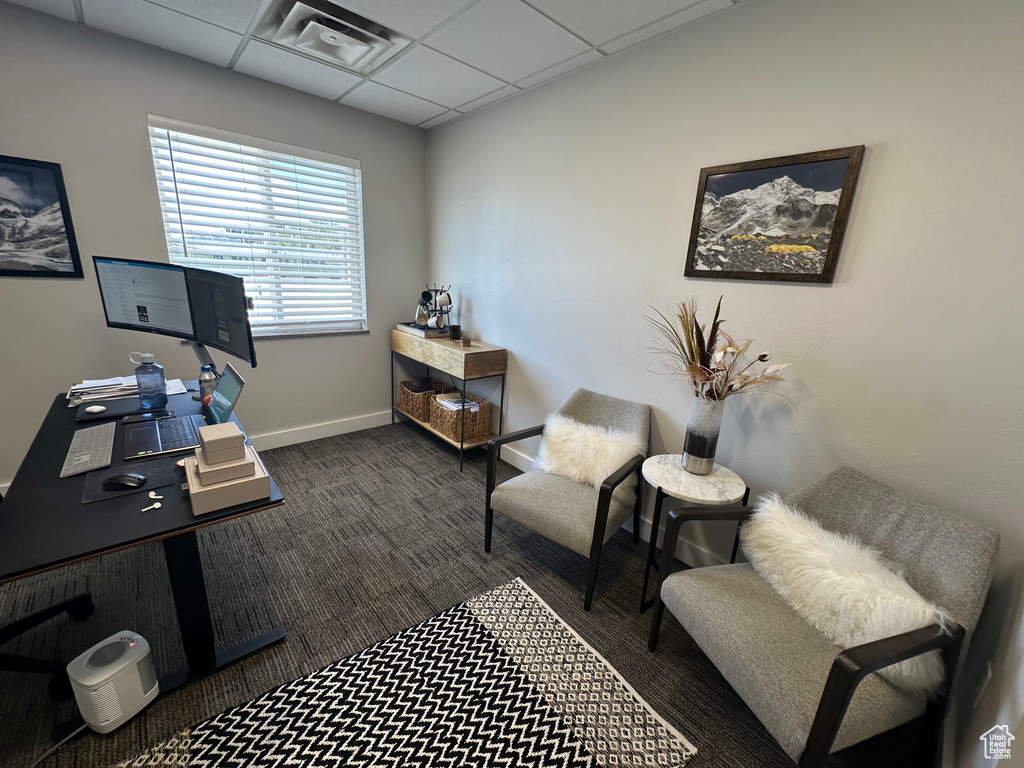 Home office with a drop ceiling and dark carpet