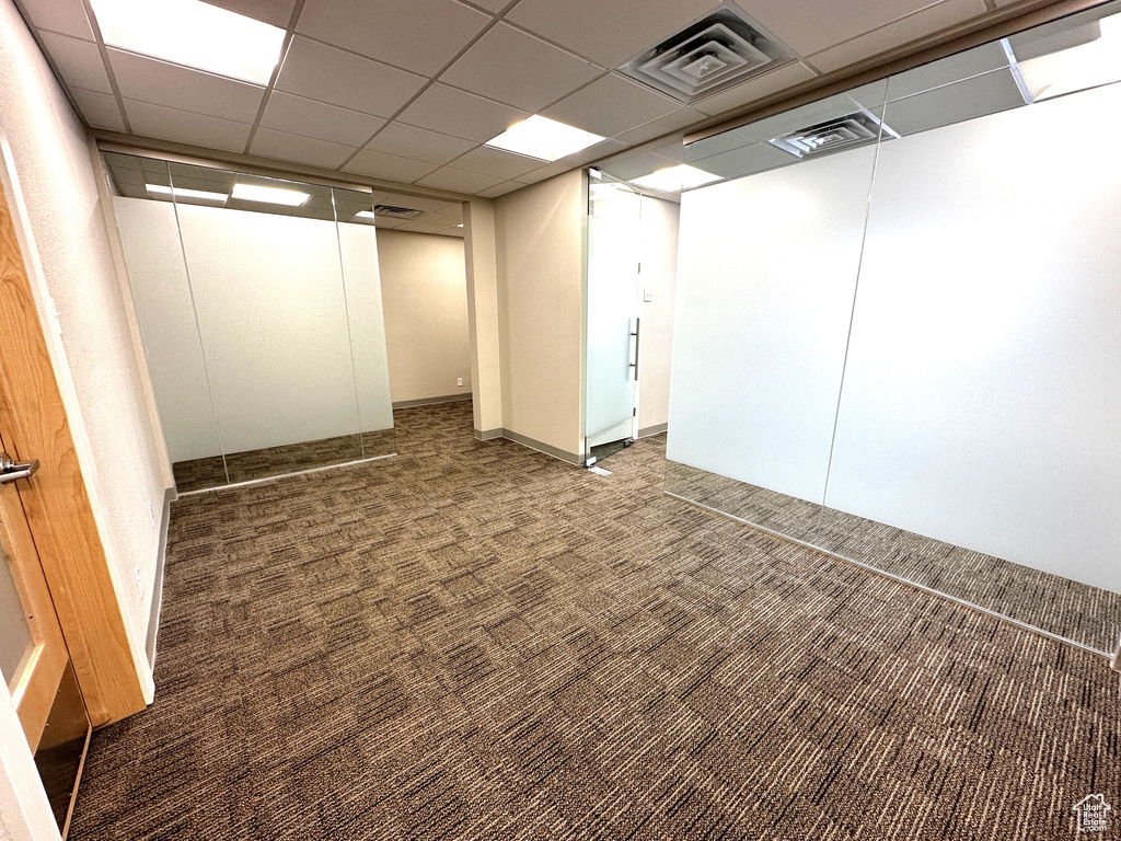 Basement featuring a paneled ceiling and dark carpet