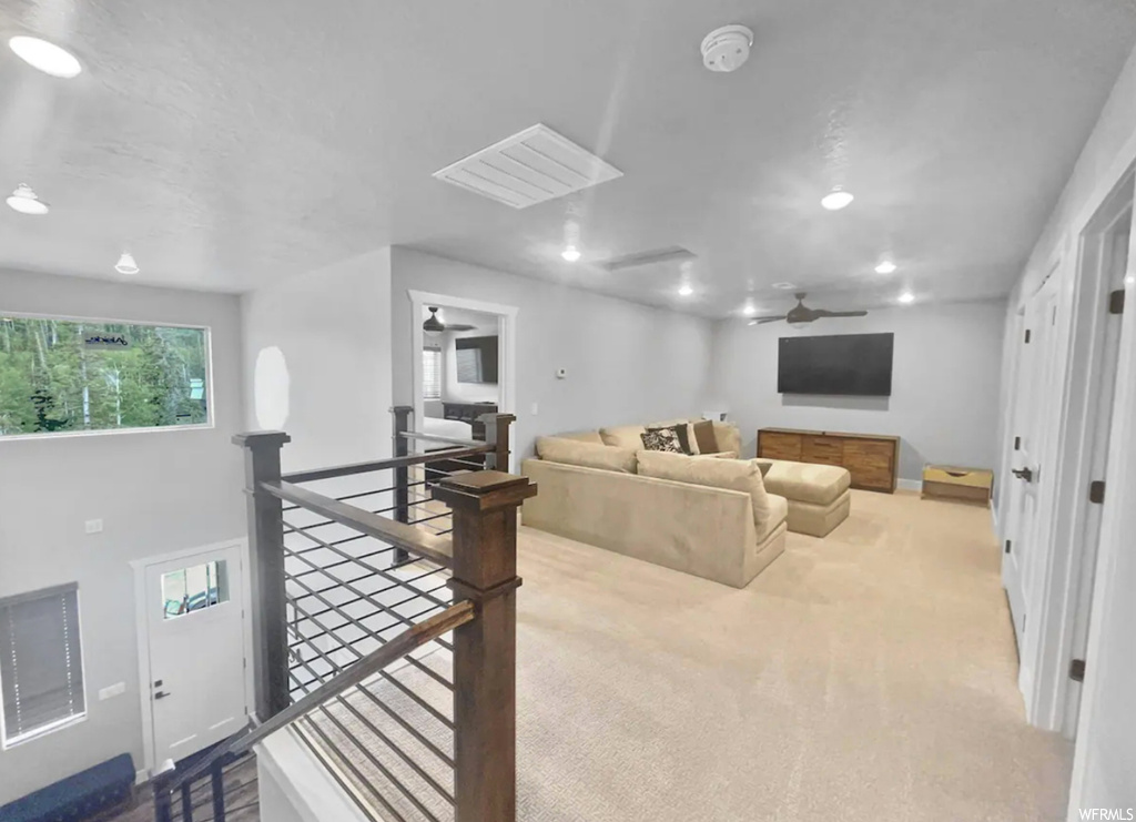 Living room featuring ceiling fan, a skylight, and light carpet