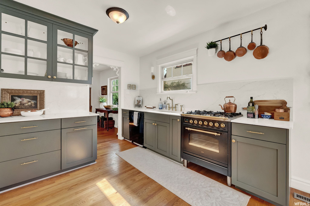 Kitchen featuring light hardwood flooring, black appliances, and light countertops