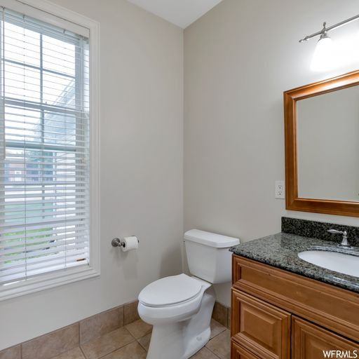 Bathroom featuring mirror, vanity, a healthy amount of sunlight, and light tile floors