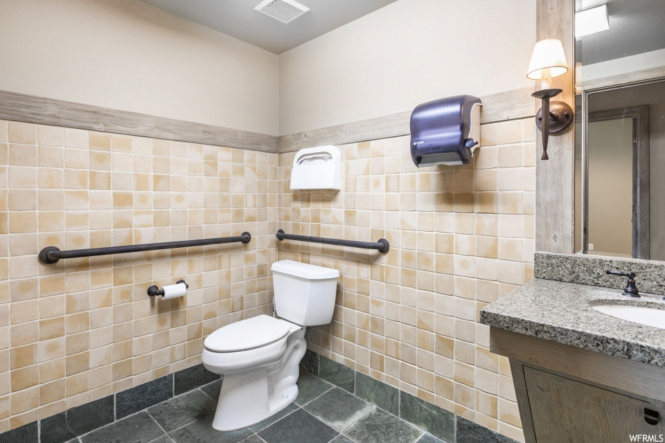 Bathroom featuring mirror, large vanity, tile flooring, and tile walls