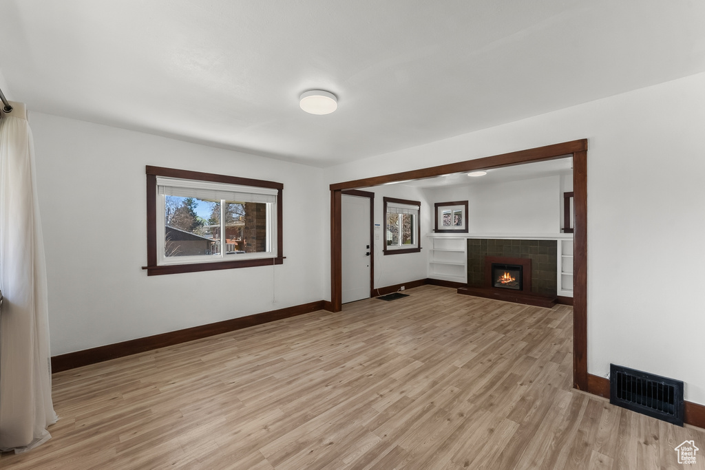 Unfurnished room featuring light hardwood / wood-style floors and a tiled fireplace