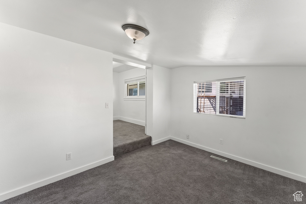Spare room with vaulted ceiling and dark carpet
