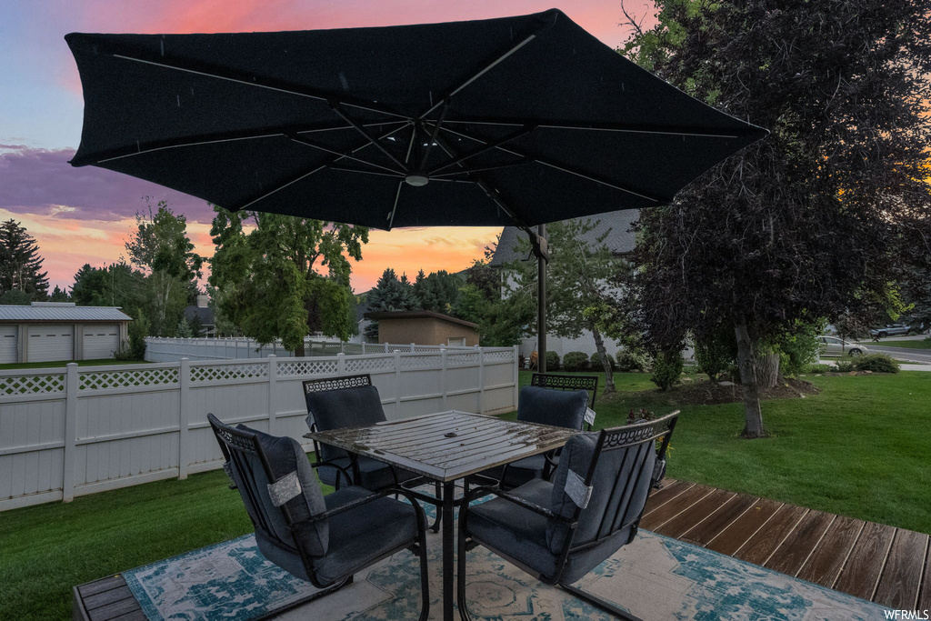 Patio terrace at dusk with a lawn and a deck