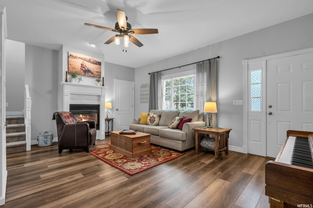 Living room featuring ceiling fan, a fireplace, and dark hardwood flooring