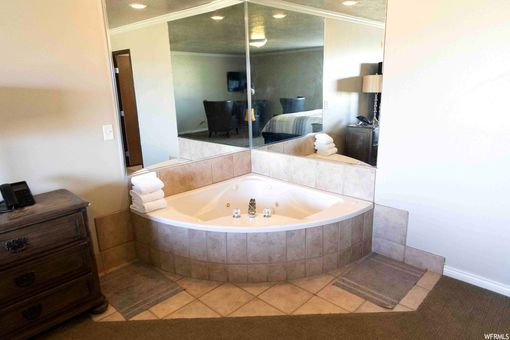 Bathroom with light tile floors, tiled bath, and ornamental molding