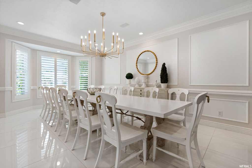 Tiled dining area featuring crown molding and a notable chandelier