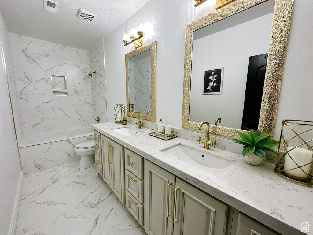 Bathroom with double sink vanity, tile flooring, a textured ceiling, and toilet