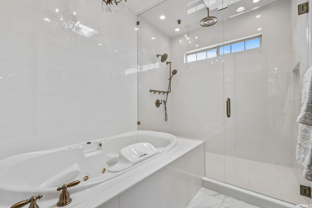 Bathroom with tile walls, independent shower and bath, and light tile floors