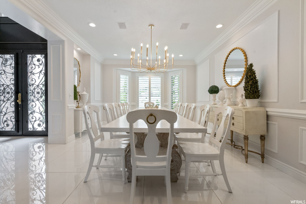 Tiled dining area with crown molding and a notable chandelier