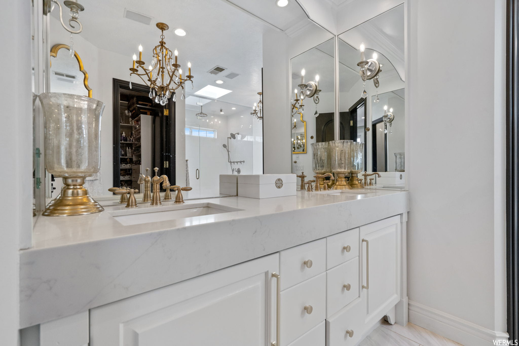 Bathroom with a chandelier, double sink vanity, tile flooring, and mirror