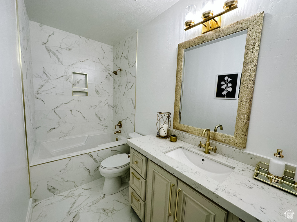 Full bathroom featuring large vanity, tiled shower / bath combo, a textured ceiling, toilet, and tile flooring