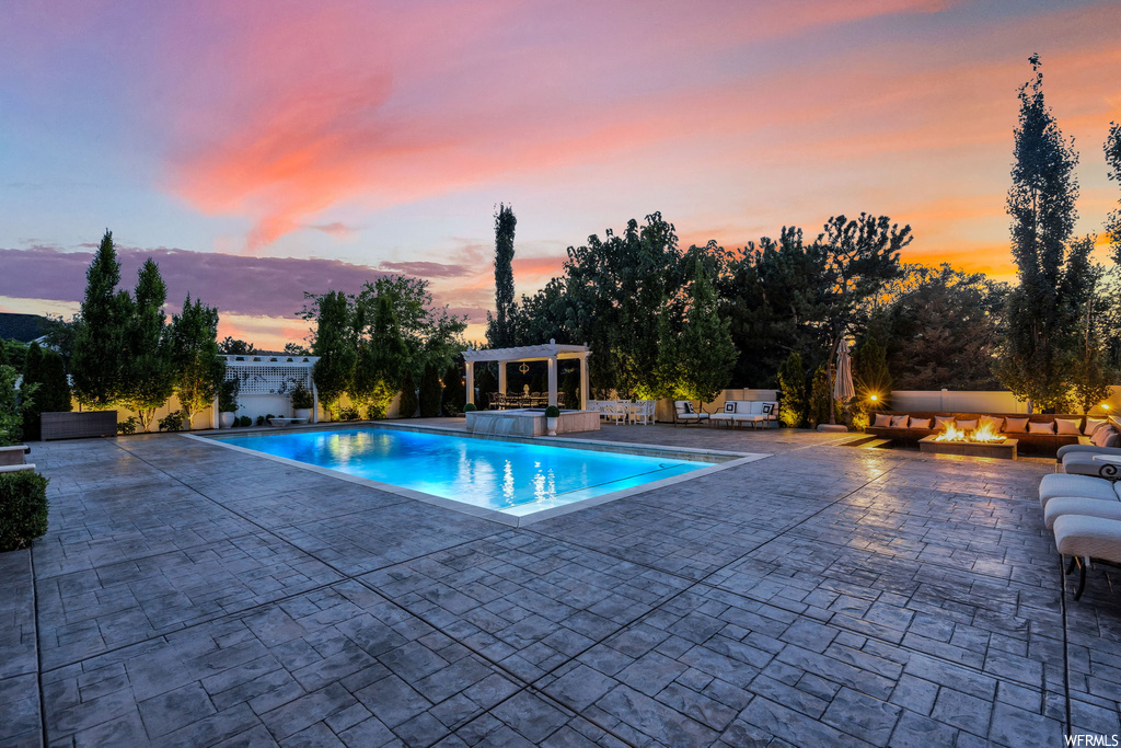 Pool at dusk featuring a patio area