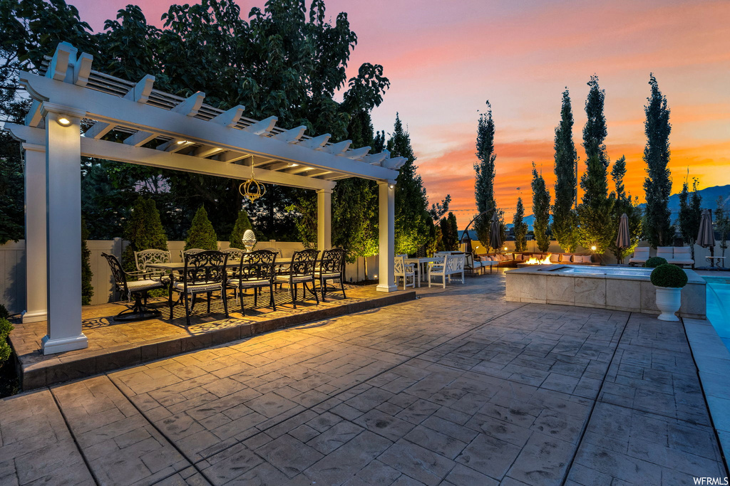 Patio terrace at dusk with a pergola and pool