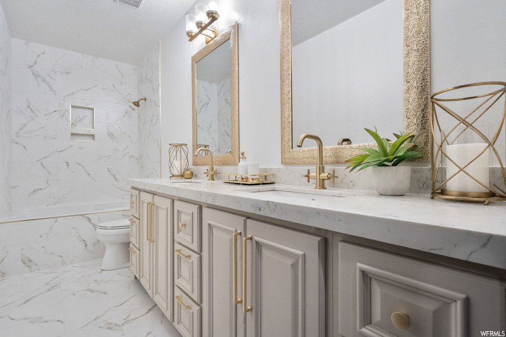 Full bathroom with light tile floors, tile walls, dual vanity, mirror, and tiled shower / bath combo