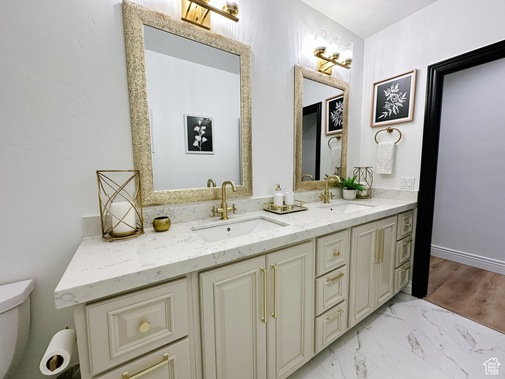 Bathroom featuring double sink, toilet, tile floors, and vanity with extensive cabinet space