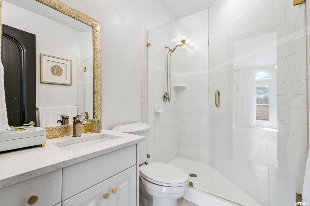 Bathroom featuring a shower with door, vanity with extensive cabinet space, and mirror