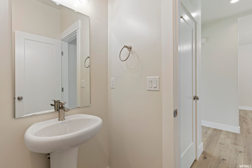 Bathroom with mirror, washbasin, and light parquet floors