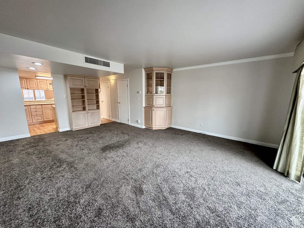 Unfurnished bedroom with ornamental molding, ensuite bath, and light colored carpet