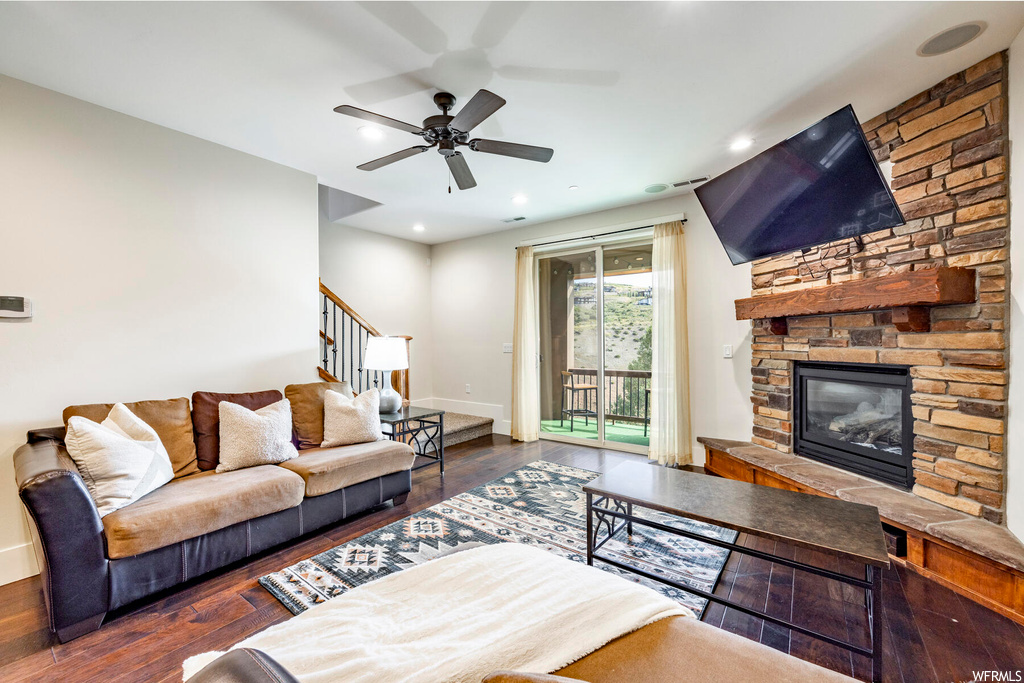 Hardwood floored living room featuring a fireplace and ceiling fan