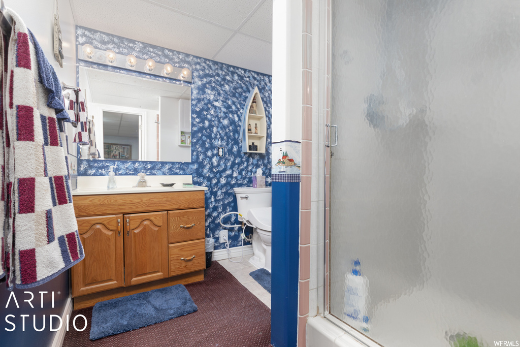 Bathroom featuring tile floors, oversized vanity, a shower with door, a drop ceiling, and mirror