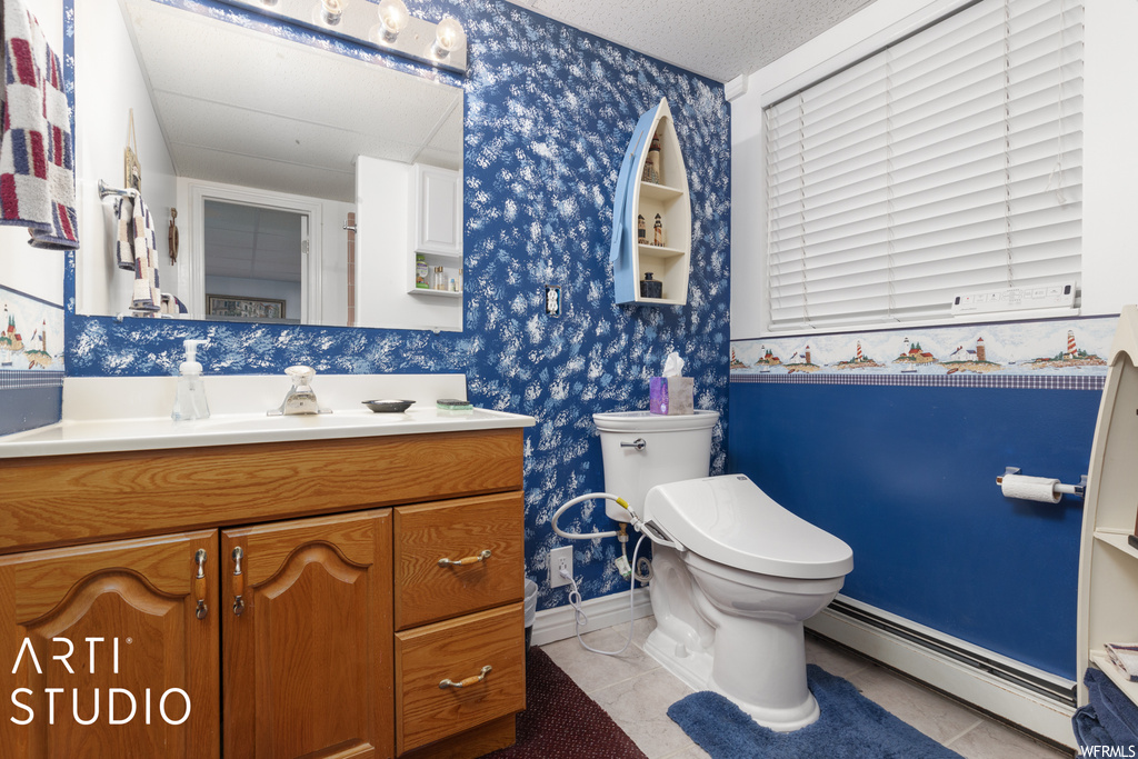 Bathroom featuring tile flooring, a baseboard heating unit, vanity, a textured ceiling, and mirror