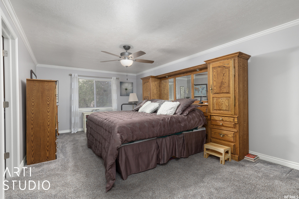 Carpeted bedroom with ceiling fan and ornamental molding