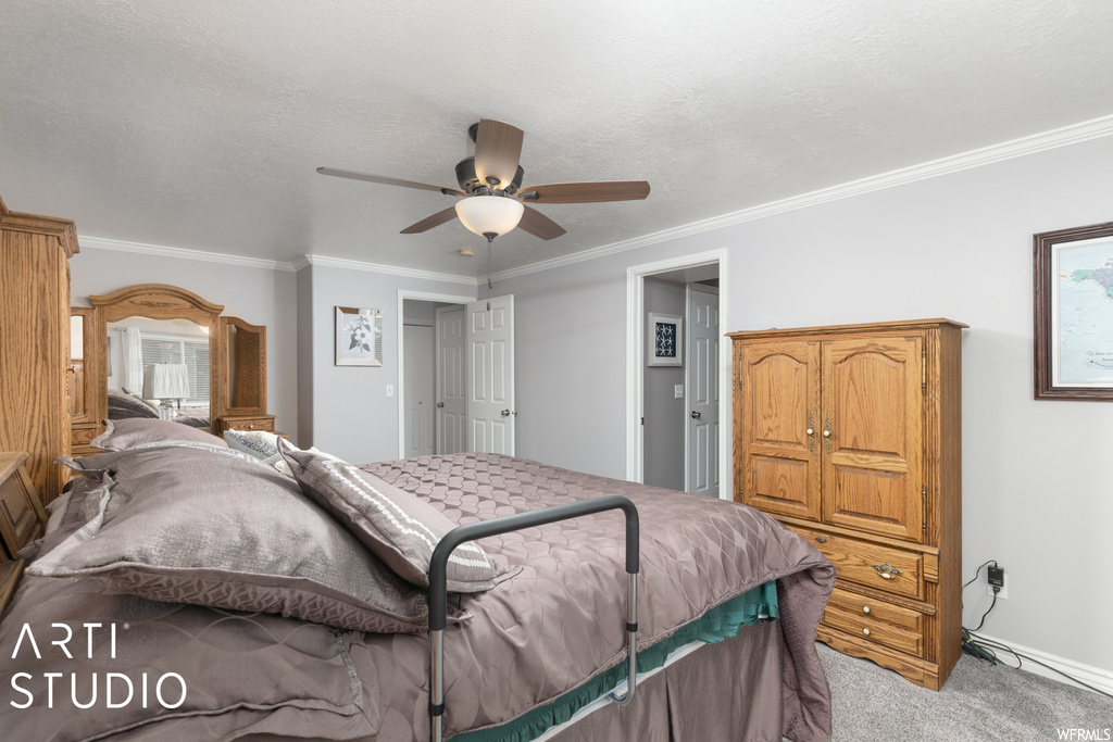 Bedroom featuring ceiling fan, carpet floors, a textured ceiling, and crown molding