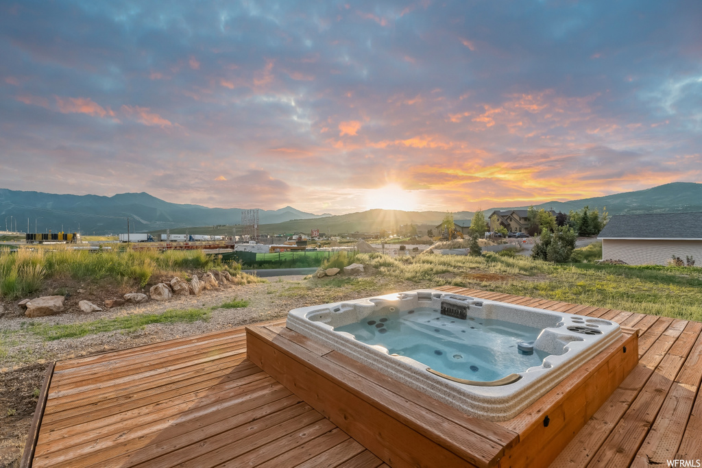 Deck at dusk featuring a mountain view and hot tub