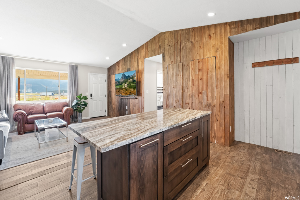 Kitchen with lofted ceiling, light hardwood flooring, wooden walls, and light countertops