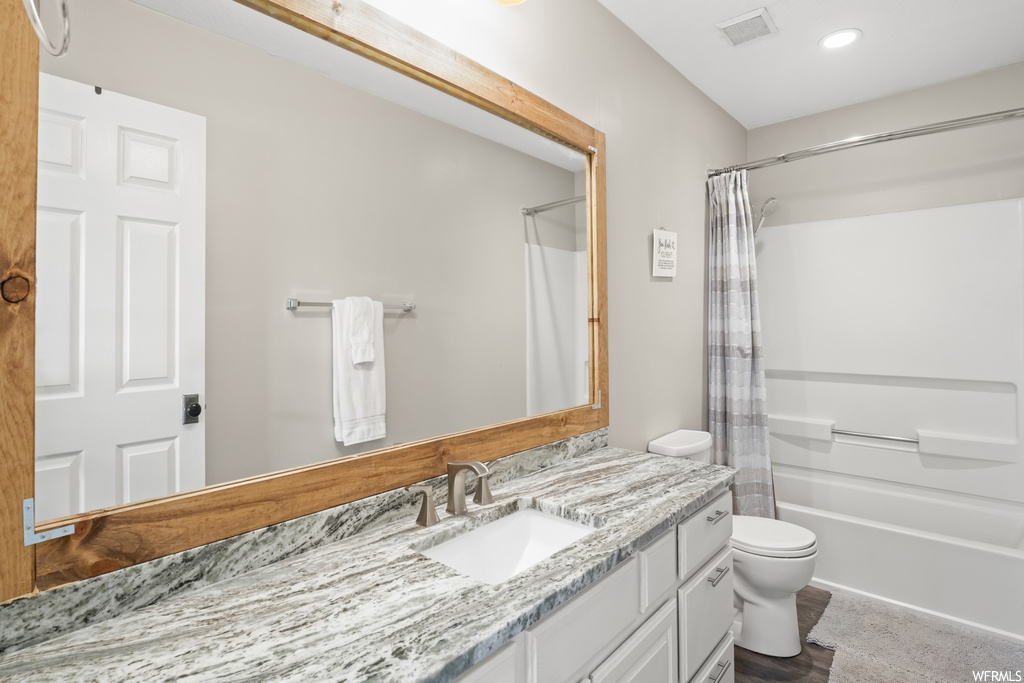 Full bathroom with mirror, shower / tub combo, light hardwood flooring, and oversized vanity