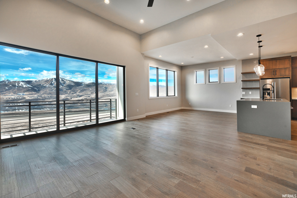 Unfurnished living room featuring sink, a towering ceiling, dark wood-type flooring, and a mountain view